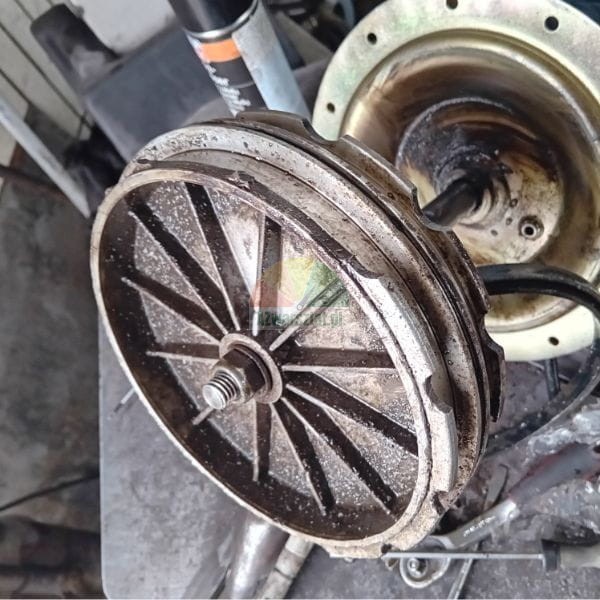 Zabrudzona metalowa część mechaniczna z żebrowaniem i nakrętką na środku