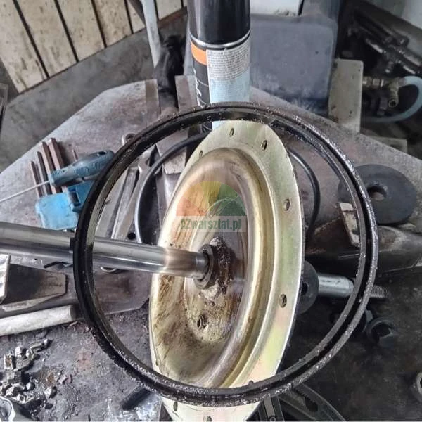 Zbliżenie na zdemontowany element mechaniczny z metalową tarczą i wałem w otoczeniu narzędzi warsztatowych