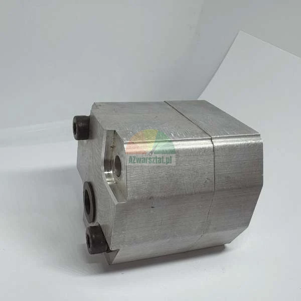 Aluminiowy korpus pompy hydraulicznej z widocznymi otworami montażowymi i śrubami imbusowymi na białym tle.