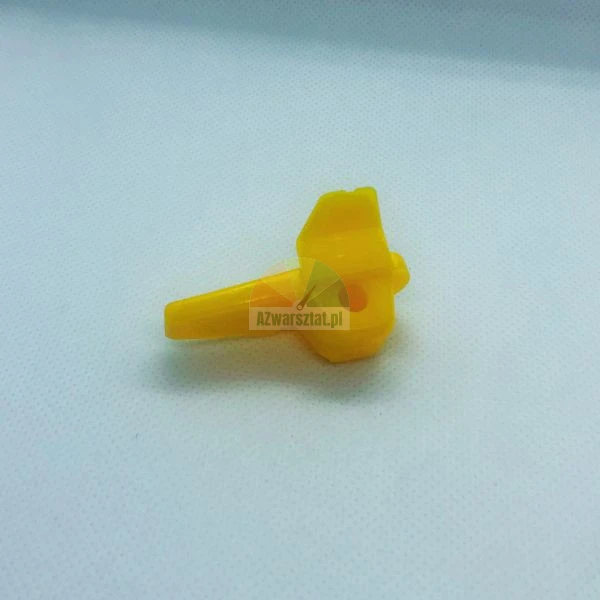 Mały żółty plastikowy element mechanizmu z otworem na oś.